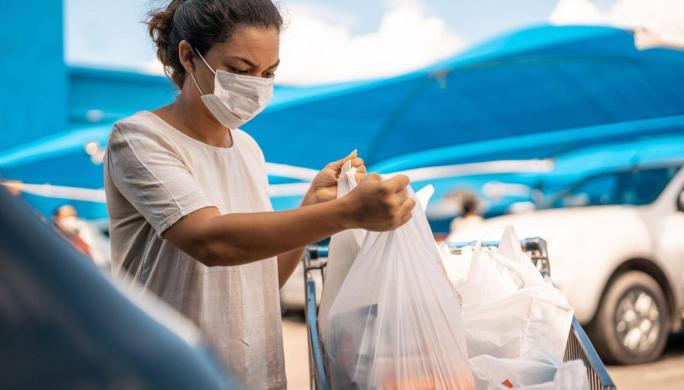 woman with face mask on grabbing groceries